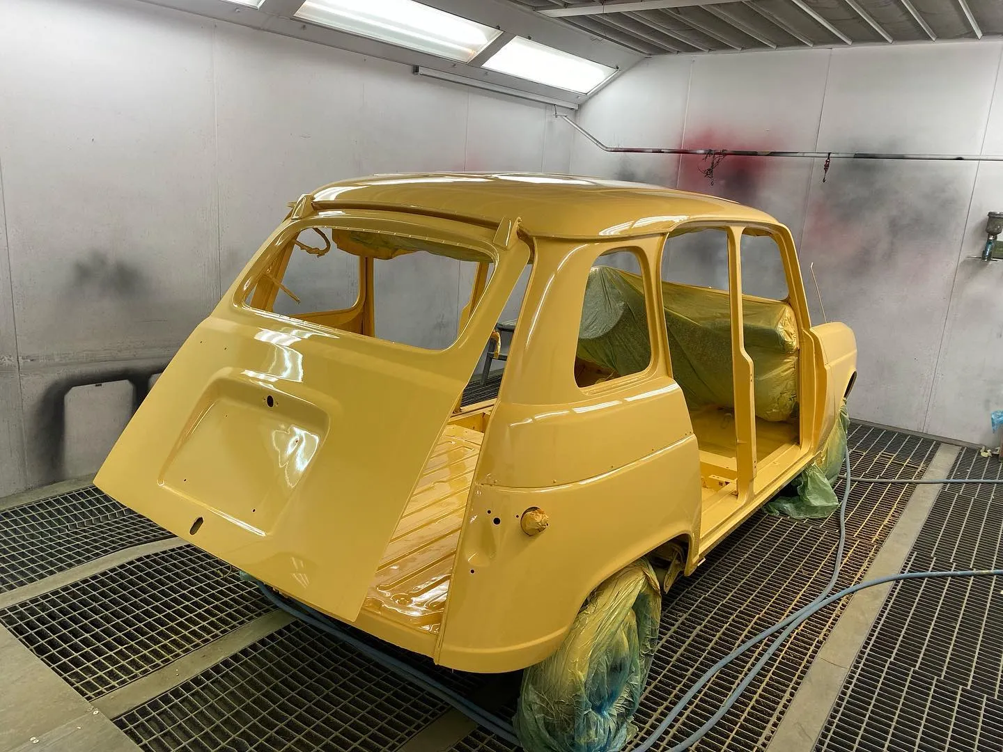 Carrocería de Renault 4 amarilla en cabina de pintura