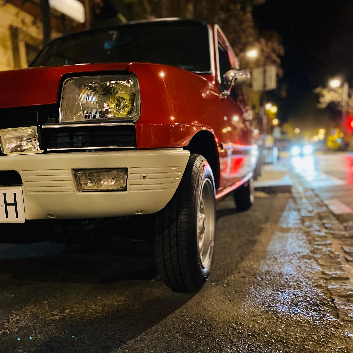 Renault 5 clásico rojo de noche en una calle mojada de Granada
