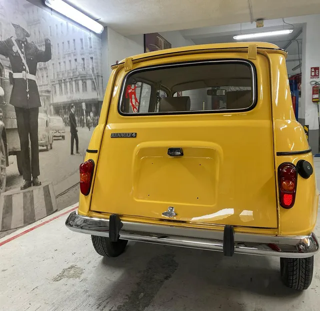 La trasera del Renault 4 amarillo ya terminada, con los cromados montados, en el garaje