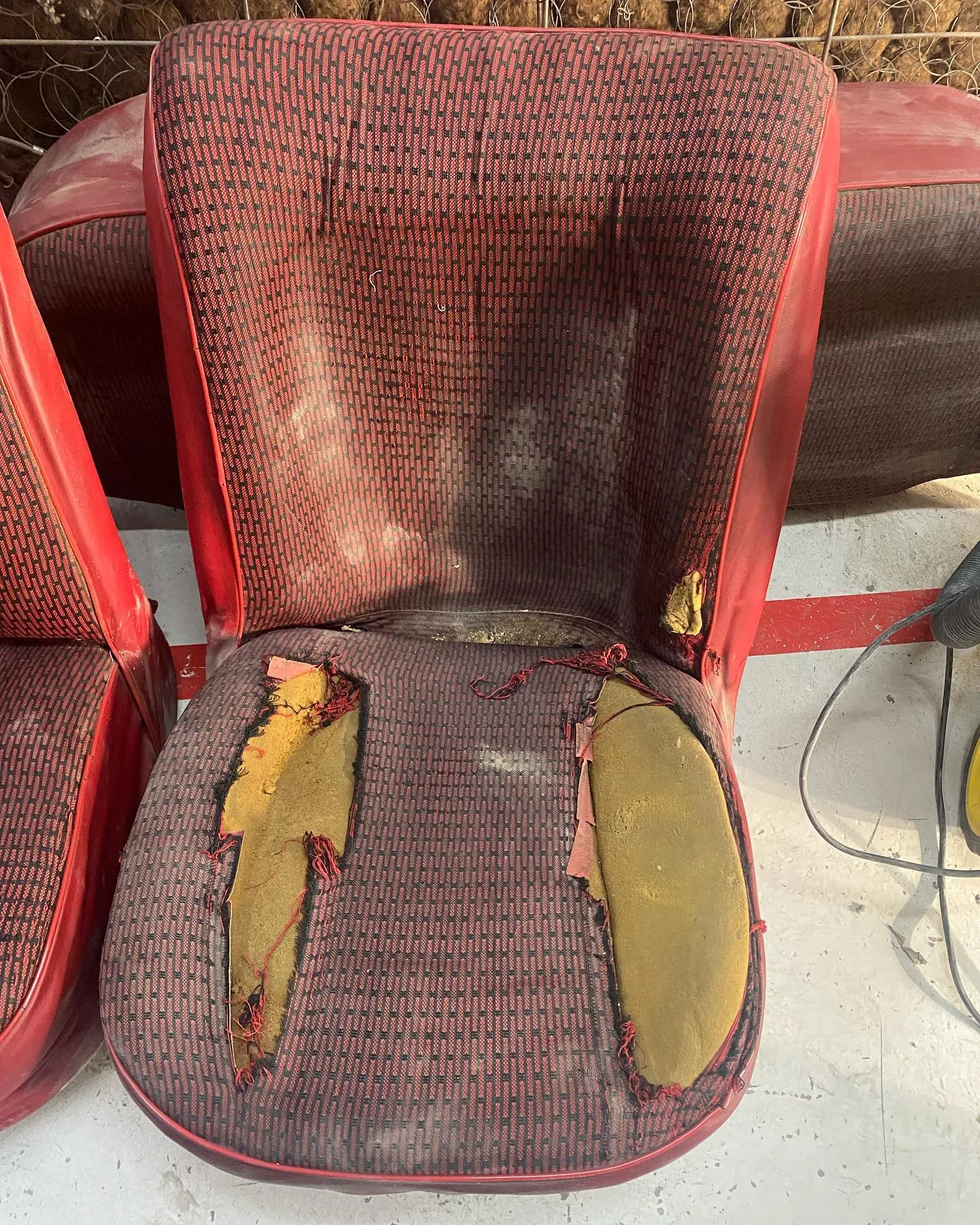 Asiento clásico con el tejido rojo desgastado y roto, con las espumas amarillentas asomando por los rotos