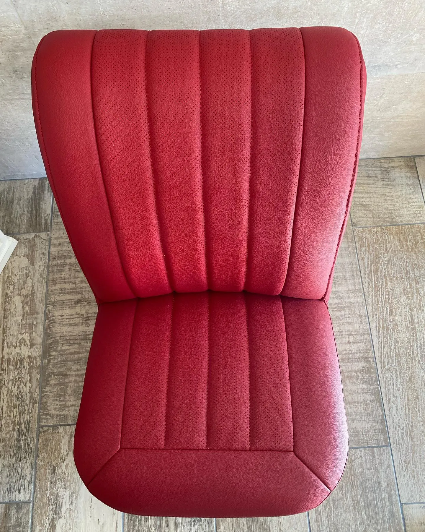 El asiento ya tapizado de nuevo en rojo, con sus pliegues cosidos y perforados, impecable